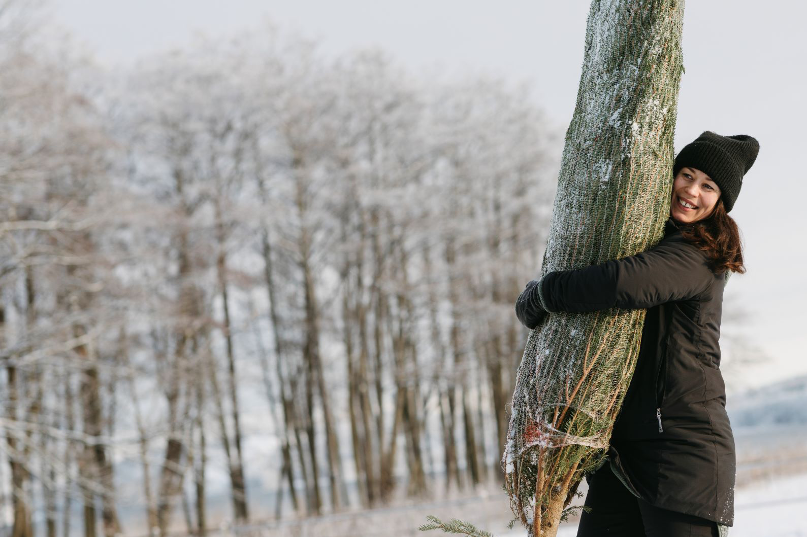 En kvinnna som bär på en gran.